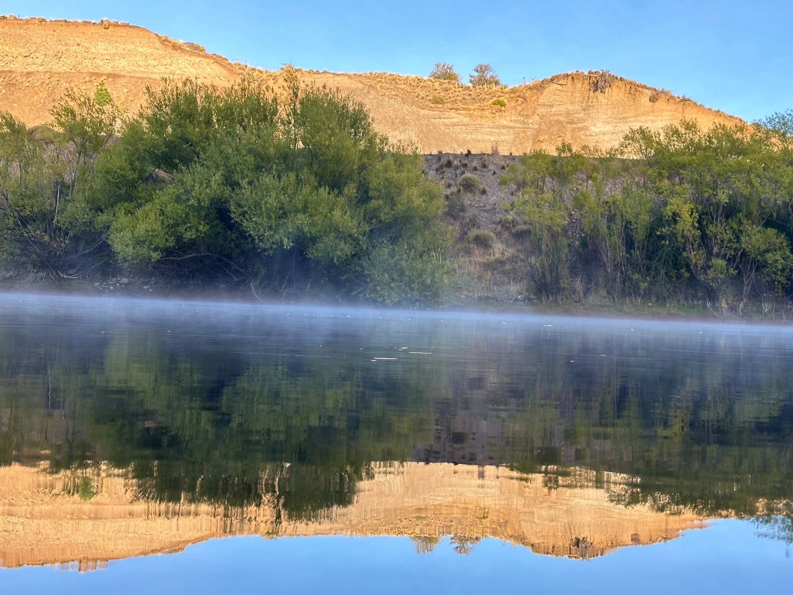 Río Limay calmo con reflejos del paisaje otoñal
