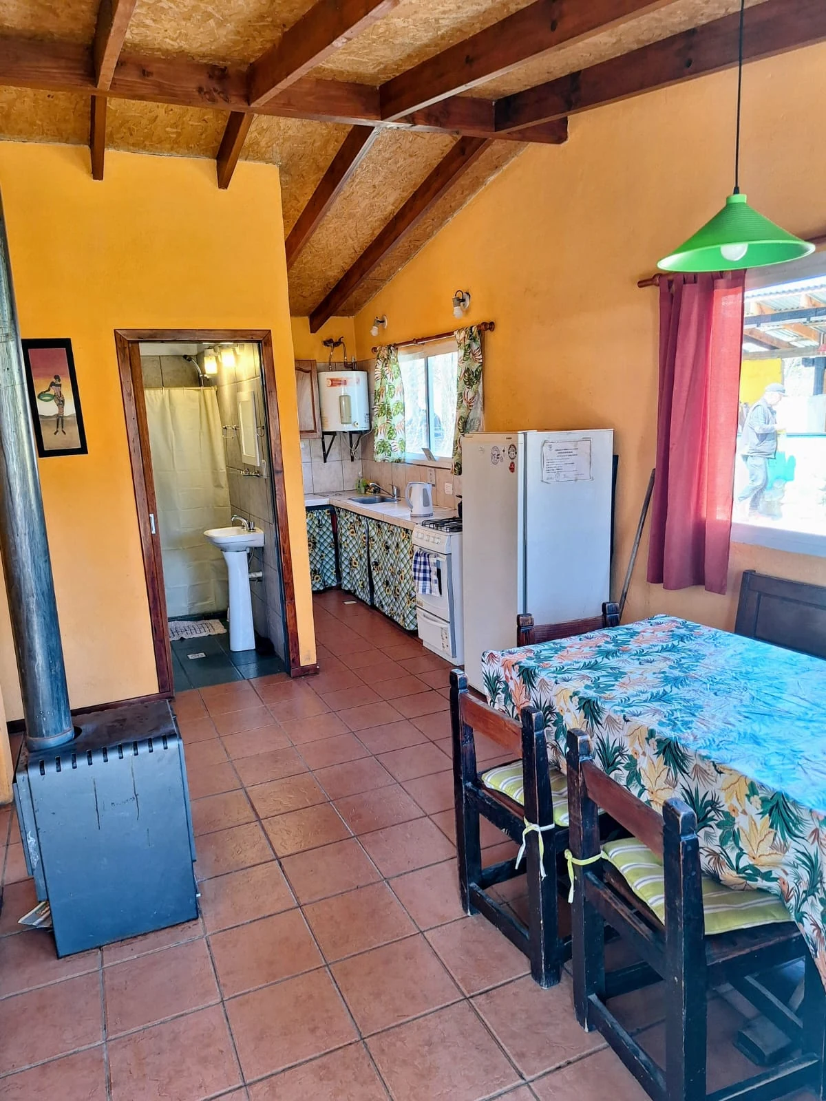 Vista interior de la cabaña con comedor, cocina y baño