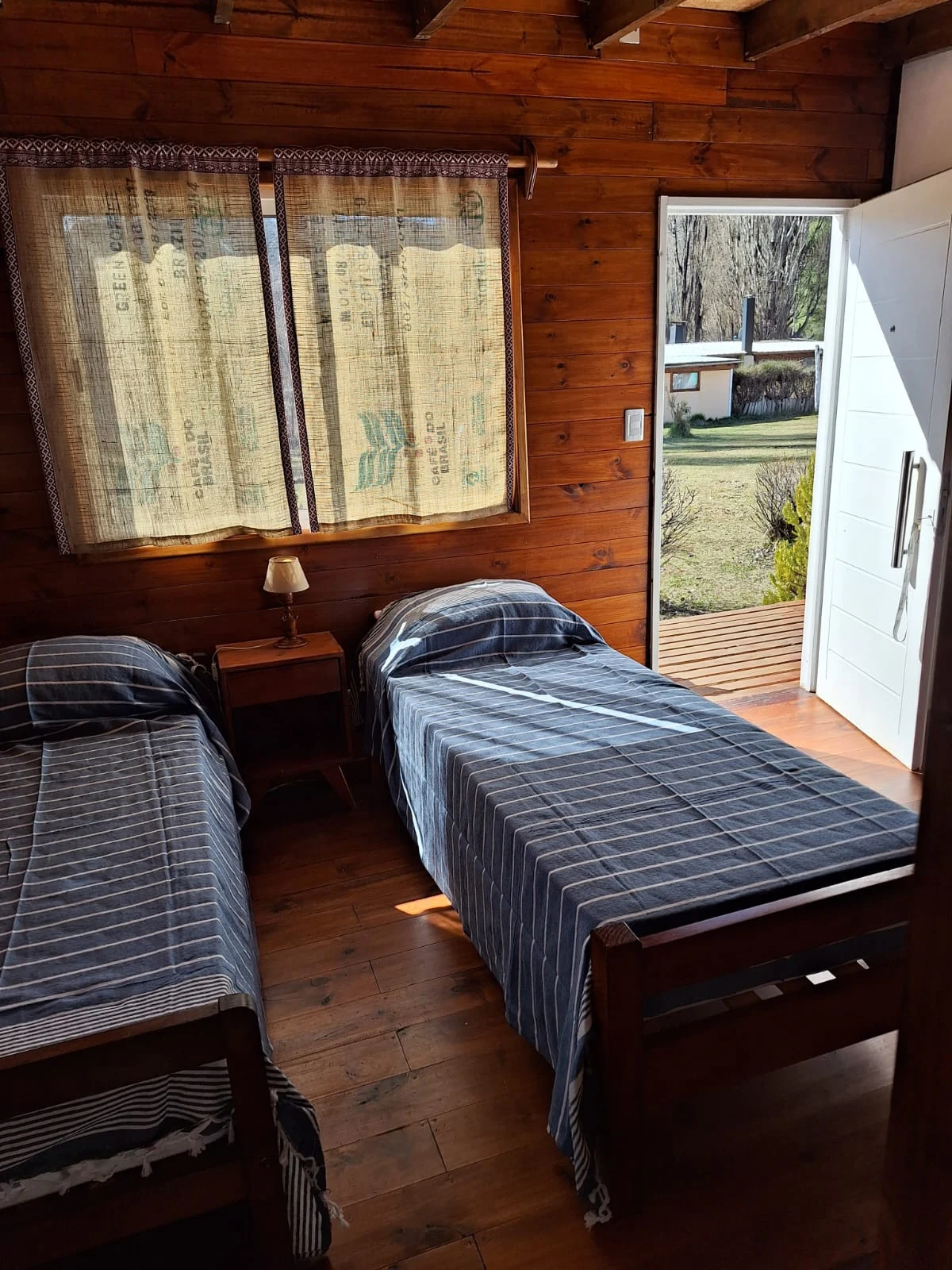 Interior de un dormi con camas y puerta hacia el exterior
